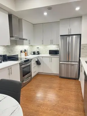 a kitchen with white cabinets and a stainless steel refrigerator at Peaceful serene oasis with free parking and wifi in Brampton