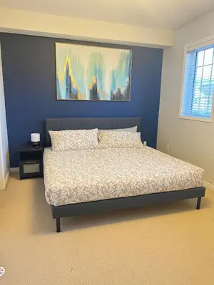 a bedroom with a bed with a blue wall at Peaceful serene oasis with free parking and wifi in Brampton