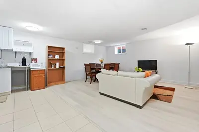 a living room with a white couch and a kitchen at Tranquil Bliss Retreat 9 min to Falls with Free Parking in Niagara Falls