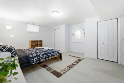 a bedroom with white walls and a bed with a blue blanket at Tranquil Bliss Retreat 9 min to Falls with Free Parking in Niagara Falls