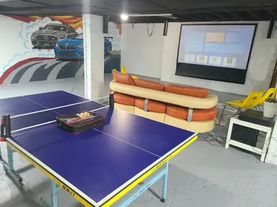 a ping pong table and a couch in a room with a screen at The Taunton House in Ajax