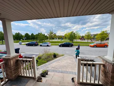 a woman walking on a porch with cars parked in a parking lot at Scarborough Spacious Private Suite 2 Queen Beds & Ensuite in Toronto