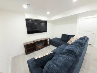 a living room with a blue couch and a tv at Niagara Cozy Suite - Modern 2Bed 15 min to Falls in Thorold