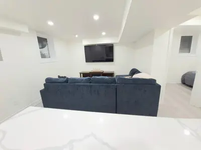 a living room with a blue couch and a tv at Niagara Cozy Suite - Modern 2Bed 15 min to Falls in Thorold