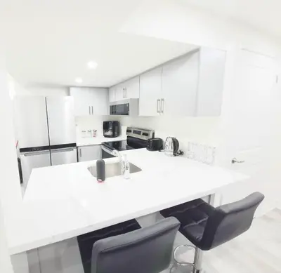 a white kitchen with a sink and two chairs at Niagara Cozy Suite - Modern 2Bed 15 min to Falls in Thorold