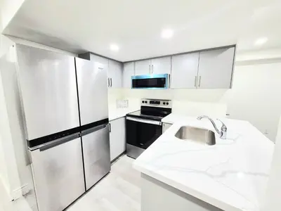 a kitchen with white cabinets and a stainless steel refrigerator at Niagara Cozy Suite - Modern 2Bed 15 min to Falls in Thorold