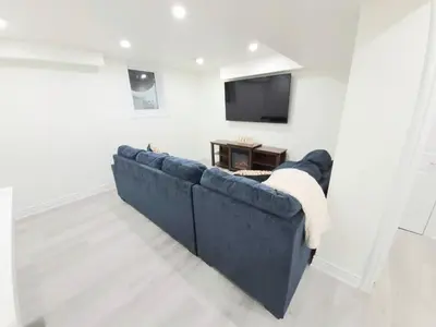 a blue couch in a living room with a tv at Niagara Cozy Suite - Modern 2Bed 15 min to Falls in Thorold