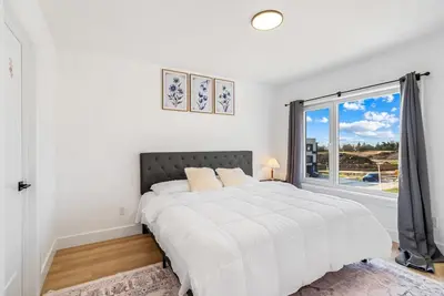 a white bedroom with a bed and a large window at Modern 3BR House, King, 2 Queens, Parking in London