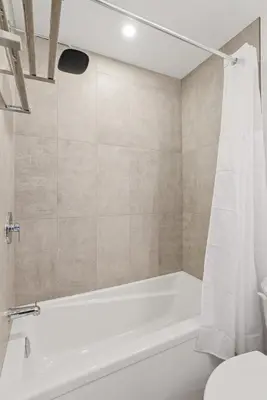 a bathroom with a white tub and a toilet at Modern 3BR House, King, 2 Queens, Parking in London