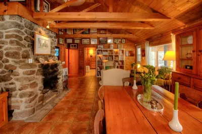 a living room with a stone fireplace and a table at Dudley House Lakeside Retreat with Access to Private Beach in Haliburton