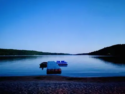 two boats sitting on the shore of a lake at Dudley House Lakeside Retreat with Access to Private Beach in Haliburton