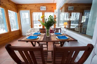 a dining room with a wooden table with a vase of flowers at Dudley House Lakeside Retreat with Access to Private Beach in Haliburton