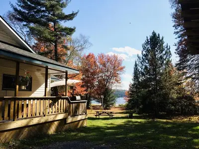 a porch of a house with a picnic table in the grass at Dudley House Lakeside Retreat with Access to Private Beach in Haliburton