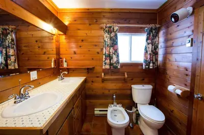 a wooden bathroom with a toilet and a sink at Dudley House Lakeside Retreat with Access to Private Beach in Haliburton