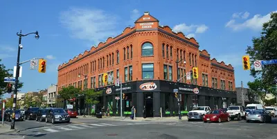 a large brick building with cars parked in front of it at 1 Bedroom basement Suite in Junction Bloor West Village in Toronto