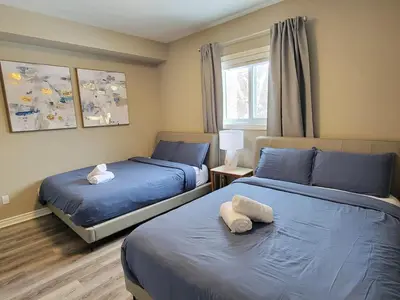 two beds in a bedroom with blue sheets and a window at Private Ski Chalet Hot Tub & Mountain Views in Blue Mountains