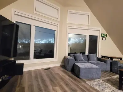 a living room with a couch and a large window at Private Ski Chalet Hot Tub & Mountain Views in Blue Mountains