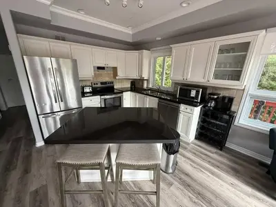 a kitchen with white cabinets and a black counter top at 5 Bedrooms, Mountain Views, Steps from Blue Mountain Village, Hot Tub, BBQ in Blue Mountains