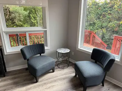 two chairs and a stool in a room with two windows at 5 Bedrooms, Mountain Views, Steps from Blue Mountain Village, Hot Tub, BBQ in Blue Mountains