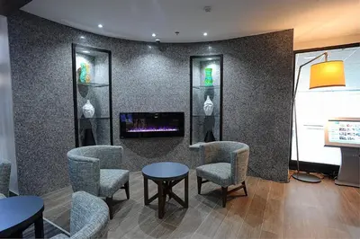 a waiting room with chairs and a tv on a wall at Holiday Inn Express & Suites Toronto Airport West by IHG in Mississauga
