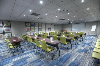 a conference room with tables and chairs and a screen at Holiday Inn Express & Suites Toronto Airport West by IHG in Mississauga