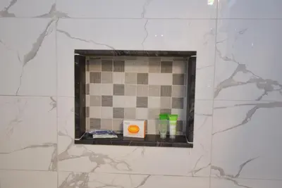 a bathroom mirror with a shelf in a tile wall at The SoMa Furnished Residences in Hamilton