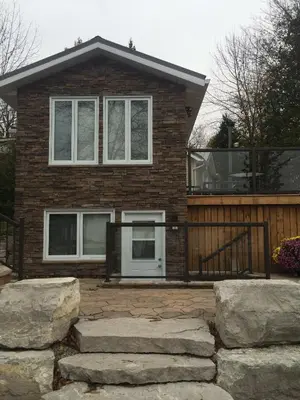 a brick house with a balcony and some rocks at Victoria Harbour Cottages in Victoria Harbour