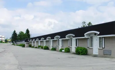 a long building with a black roof and a sidewalk at Travellers Inn in Hanover