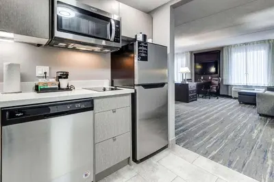 a kitchen with a stainless steel refrigerator and a living room at Hampton Inn & Suites by Hilton Brantford in Brantford