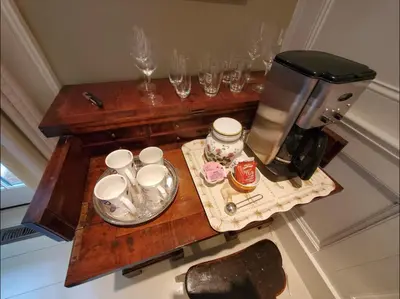 a table with a coffee maker and glasses on it at Dot's Landing Garden Room in Niagara on the Lake