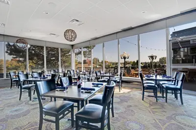 a dining room with tables and chairs and large windows at Holiday Inn Hotel Peterborough Waterfront by IHG in Peterborough