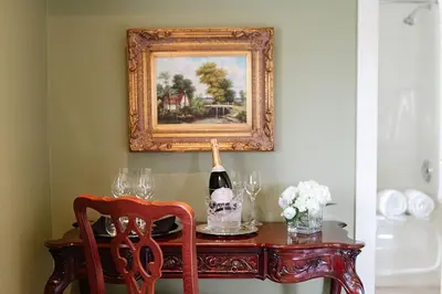 a table with a bottle of wine and a picture at Riverbend Inn & Vineyard in Niagara on the Lake
