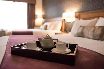 a tray with two cups and a tea set on a bed at Cambridge Hotel and Conference Centre in Cambridge