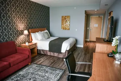 a hotel room with a bed and a red couch at Cambridge Hotel and Conference Centre in Cambridge