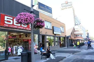 a city street with people sitting on benches in front of stores at The Falls Family Lodge in Niagara Falls