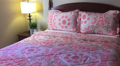 a bed with a red and white blanket and pillows at The Falls Family Lodge in Niagara Falls