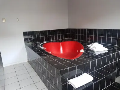 a black tiled bathroom with a red bath tub at 7 Nights Stay in Niagara Falls