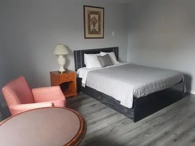 a bedroom with a bed and a chair and a table at 7 Nights Stay in Niagara Falls