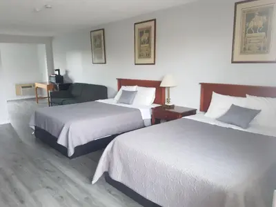 a hotel room with two beds and a chair at 7 Nights Stay in Niagara Falls