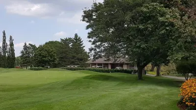 a golf green with a tree and a house at River Rapids Inn in Niagara Falls