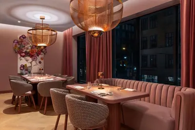 a restaurant with two tables and chairs and chandeliers at Revery Toronto Downtown, Curio Collection by Hilton in Toronto