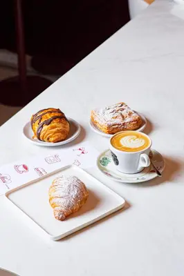 a table with two plates of pastries and a cup of coffee at Revery Toronto Downtown, Curio Collection by Hilton in Toronto