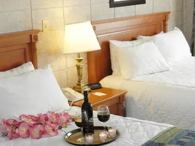 a hotel room with two beds and a bottle of wine and flowers at Capri Inn in St. Catharines
