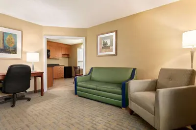 a living room with a green couch and a chair at Travelodge by Wyndham Oshawa Whitby in Oshawa