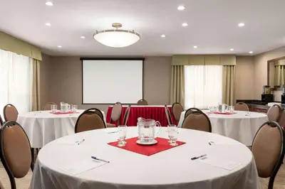a conference room with two tables and a projector screen at Travelodge by Wyndham Oshawa Whitby in Oshawa