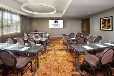 a conference room with tables and chairs and a screen at Doubletree by Hilton Toronto Airport, ON in Toronto