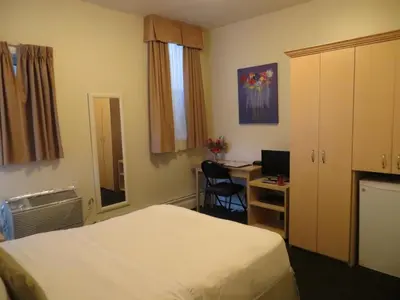 a hotel room with two beds and a desk with a computer at Victoria's Mansion Guest House in Toronto
