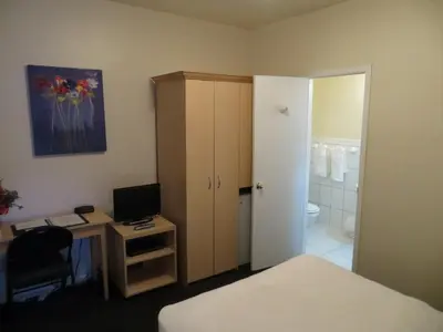 a bedroom with a bed and a desk with a television at Victoria's Mansion Guest House in Toronto