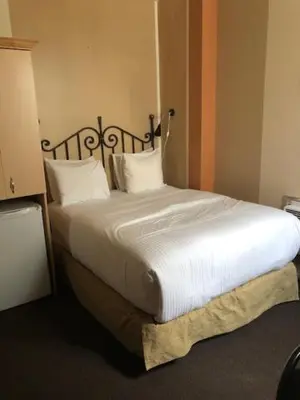a bedroom with a large bed with white sheets and pillows at Victoria's Mansion Guest House in Toronto