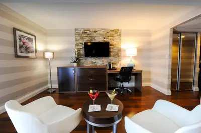 a living room with two white chairs and a tv at Holiday Inn Niagara Falls-By the Falls by IHG in Niagara Falls